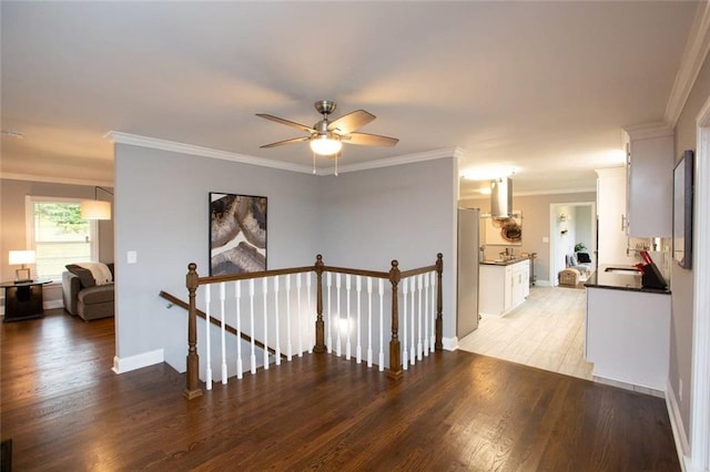 hall with a sink, an upstairs landing, baseboards, light wood-style floors, and ornamental molding