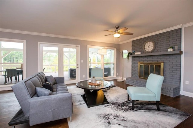 living room featuring ornamental molding, a brick fireplace, wood finished floors, and a healthy amount of sunlight