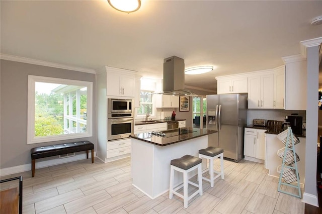 kitchen with tasteful backsplash, island range hood, appliances with stainless steel finishes, white cabinetry, and a sink