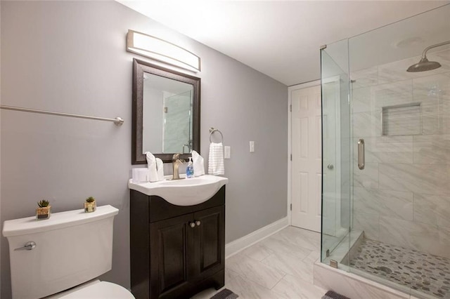 bathroom featuring marble finish floor, toilet, a shower stall, vanity, and baseboards