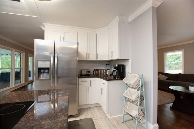 kitchen with crown molding, stainless steel refrigerator with ice dispenser, tasteful backsplash, white cabinetry, and black electric cooktop