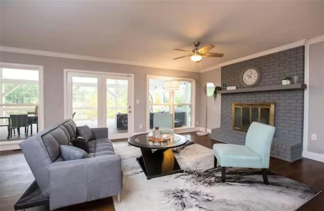 living room featuring baseboards, ceiling fan, wood finished floors, crown molding, and a brick fireplace