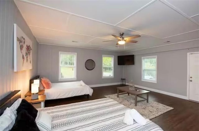 bedroom featuring a ceiling fan, multiple windows, baseboards, and wood finished floors