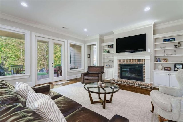 living room with built in shelves, french doors, crown molding, a fireplace, and hardwood / wood-style floors