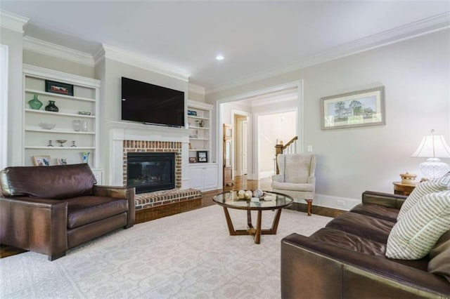 living room with built in shelves, ornamental molding, a fireplace, and light hardwood / wood-style flooring