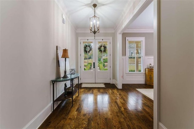 foyer entrance with french doors, ornamental molding, dark hardwood / wood-style flooring, and a notable chandelier