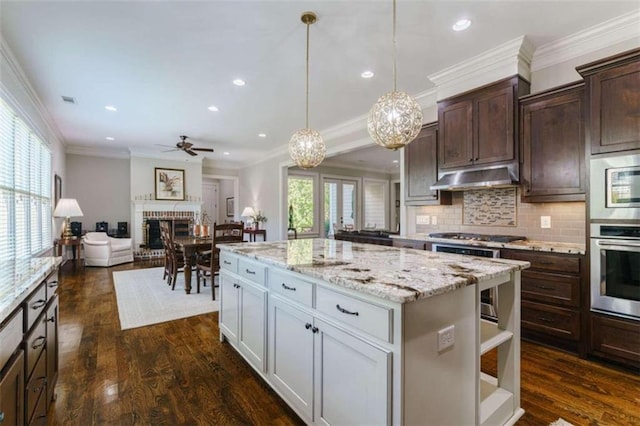 kitchen featuring dark hardwood / wood-style flooring, hanging light fixtures, a center island, and a brick fireplace