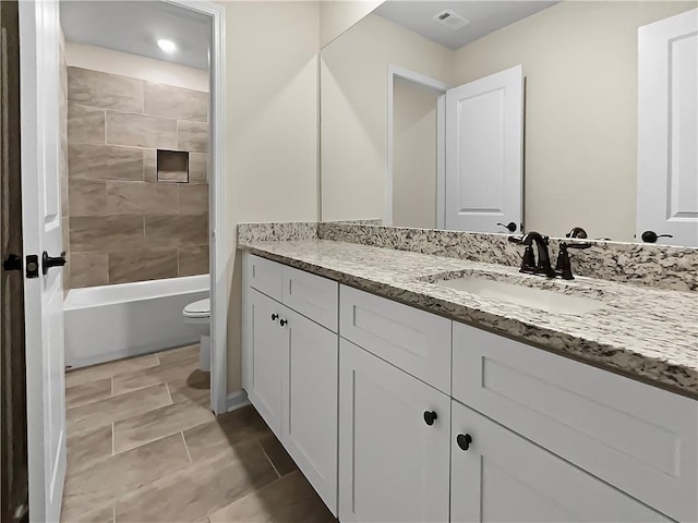 full bathroom with toilet, tiled shower / bath combo, and vanity