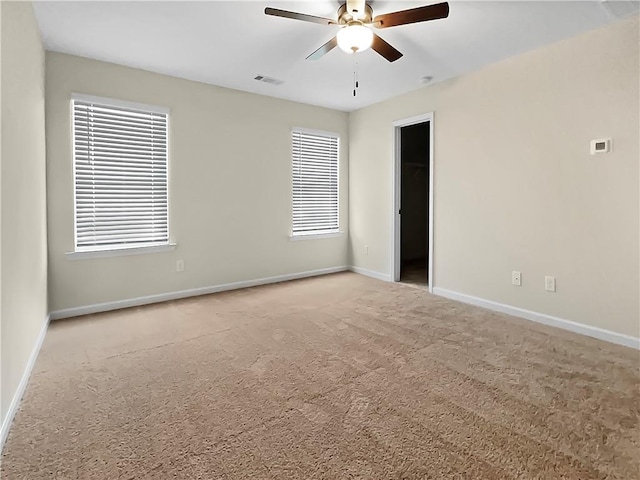 carpeted empty room with ceiling fan and plenty of natural light