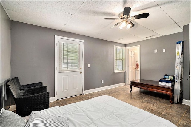 tiled bedroom featuring baseboards, multiple windows, and a paneled ceiling