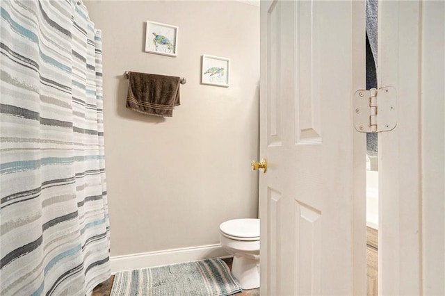 full bath featuring baseboards, toilet, and curtained shower