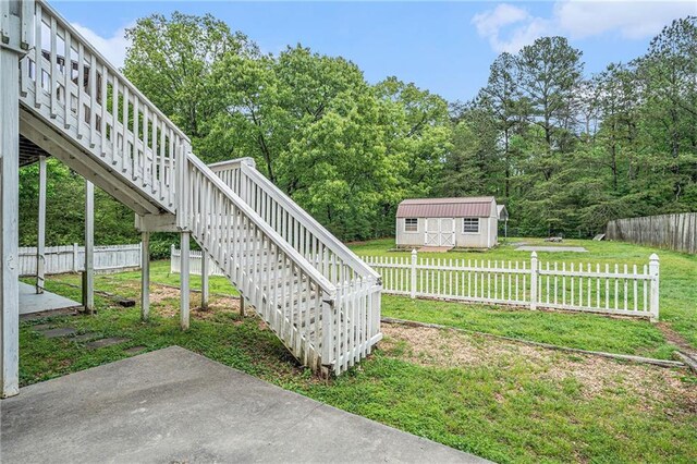view of yard featuring stairs, fence, an outbuilding, and a shed
