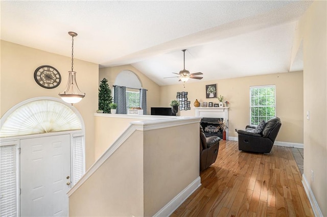 foyer with ceiling fan, a fireplace, baseboards, wood-type flooring, and lofted ceiling