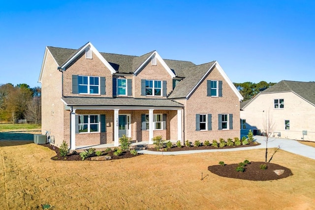 craftsman-style house with a front lawn, central AC unit, and covered porch