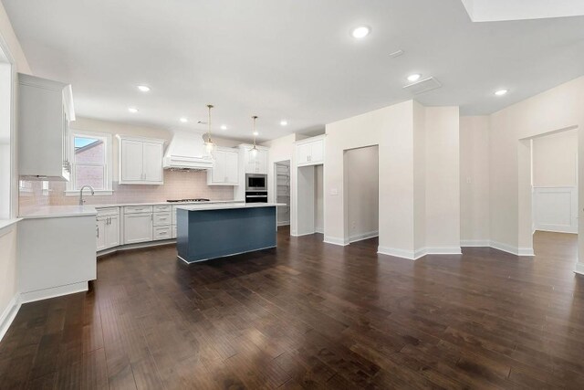 kitchen featuring a kitchen island, premium range hood, decorative light fixtures, and dark hardwood / wood-style flooring