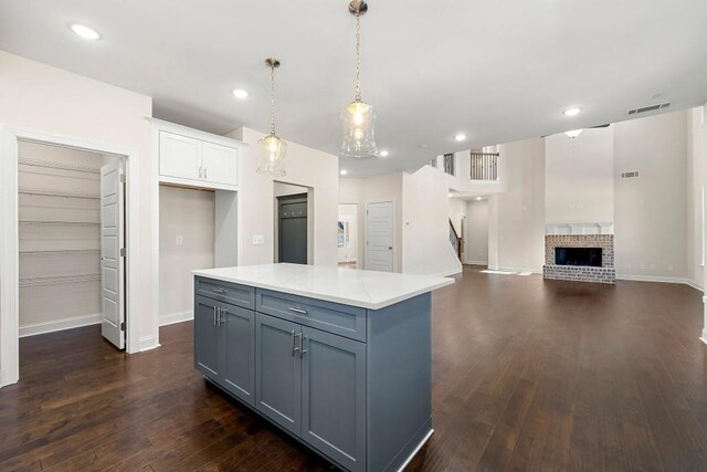 kitchen with white cabinetry, dark hardwood / wood-style floors, a fireplace, gray cabinets, and hanging light fixtures