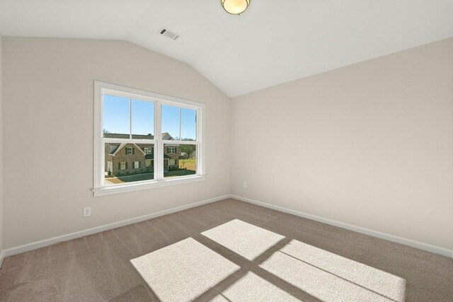 carpeted spare room featuring vaulted ceiling