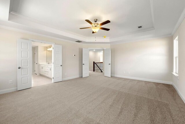 unfurnished bedroom featuring ornamental molding, connected bathroom, light carpet, ceiling fan, and a raised ceiling