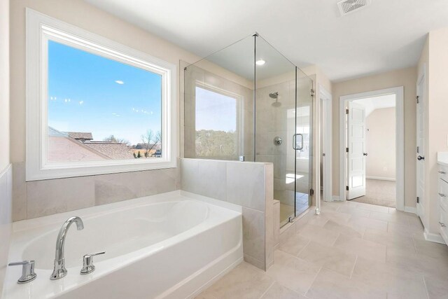 bathroom with a wealth of natural light, tile patterned flooring, plus walk in shower, and vanity