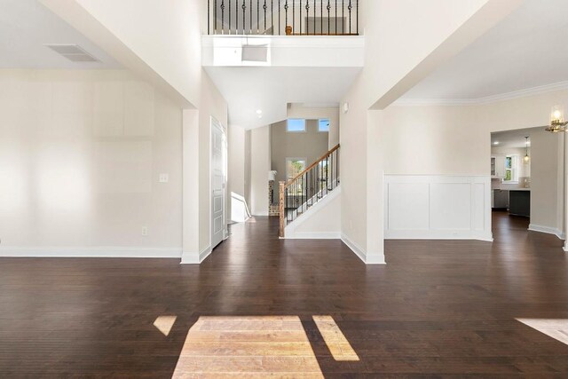 entrance foyer with dark hardwood / wood-style flooring, crown molding, and a towering ceiling