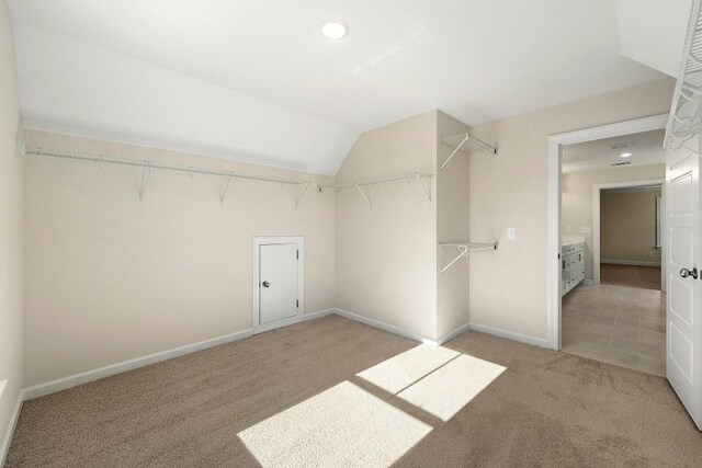 spacious closet with lofted ceiling and light colored carpet