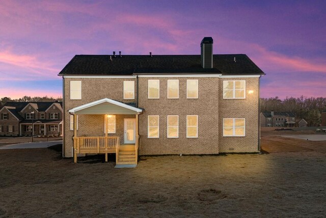 back house at dusk featuring a deck