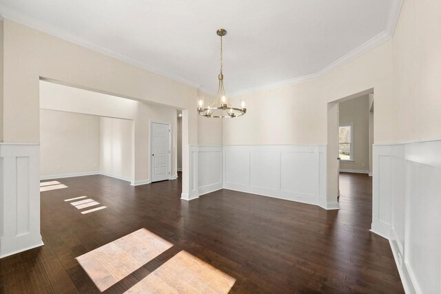 unfurnished dining area featuring ornamental molding, a chandelier, and dark hardwood / wood-style flooring