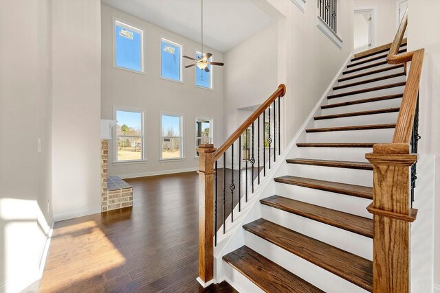 stairway featuring hardwood / wood-style floors, a high ceiling, and ceiling fan