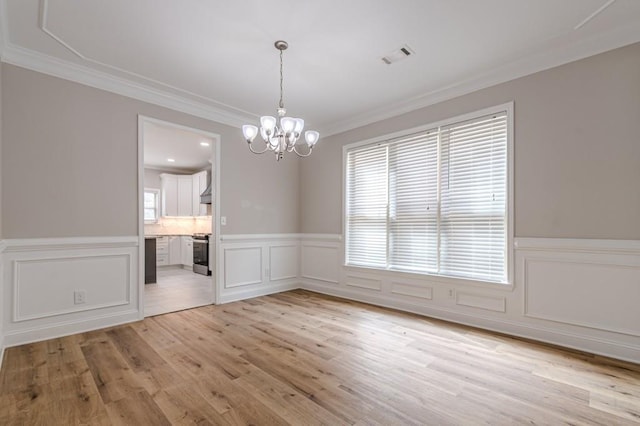 unfurnished dining area with ornamental molding, light hardwood / wood-style flooring, and a chandelier