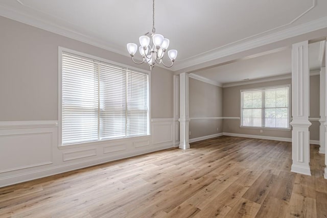 unfurnished dining area featuring ornamental molding, decorative columns, light hardwood / wood-style floors, and an inviting chandelier