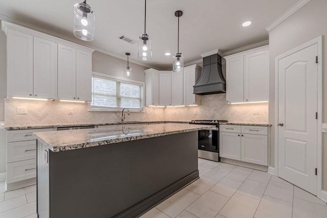 kitchen featuring decorative backsplash, white cabinetry, crown molding, stainless steel range oven, and premium range hood