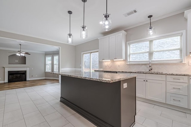 kitchen featuring ceiling fan, white cabinets, hanging light fixtures, tasteful backsplash, and a kitchen island