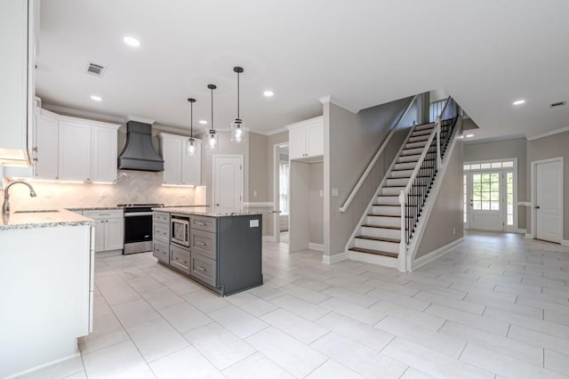 kitchen featuring a kitchen island, custom exhaust hood, stainless steel appliances, and white cabinetry