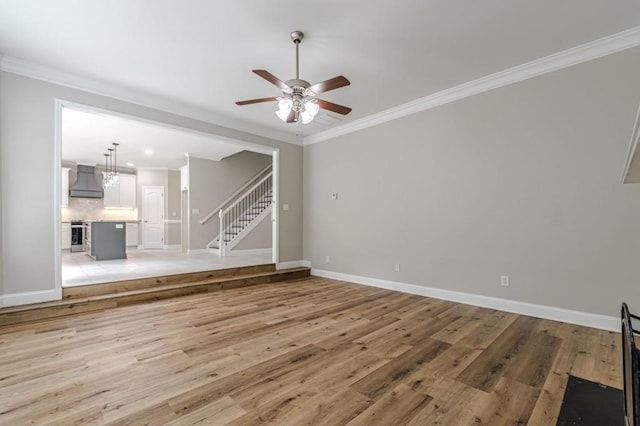 unfurnished living room featuring ceiling fan with notable chandelier, light hardwood / wood-style floors, and crown molding