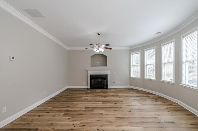 unfurnished living room featuring light hardwood / wood-style flooring, ornamental molding, ceiling fan, and a healthy amount of sunlight