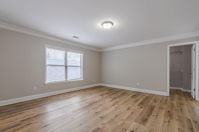 unfurnished room with ornamental molding and light wood-type flooring