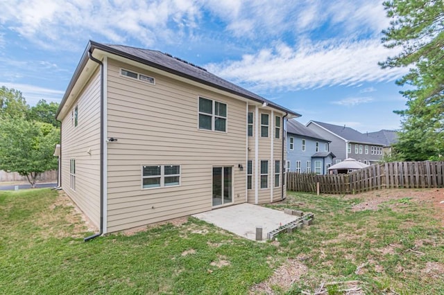 back of property with a lawn and a patio