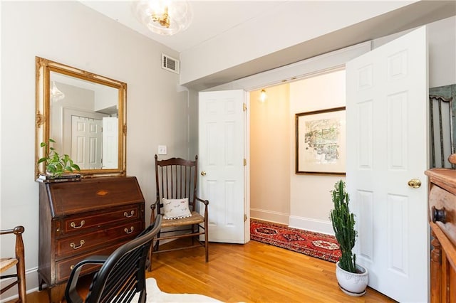 living area with baseboards, wood finished floors, and visible vents