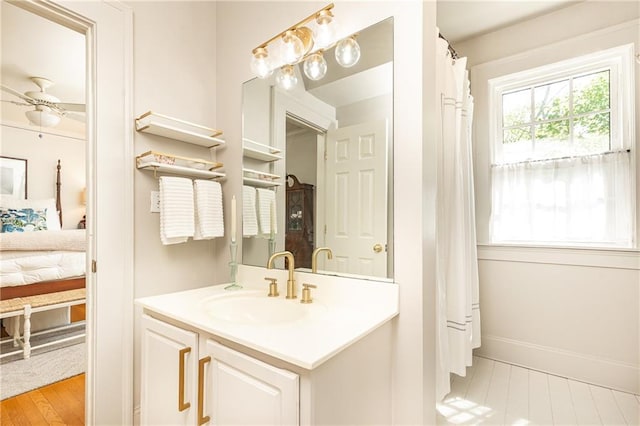 full bath featuring ensuite bath, vanity, and baseboards