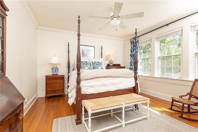 bedroom with wood finished floors, crown molding, baseboards, and ceiling fan