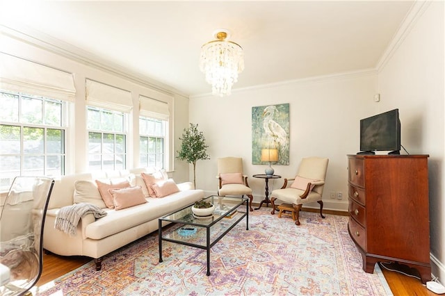 living area with baseboards, ornamental molding, a chandelier, and light wood-type flooring