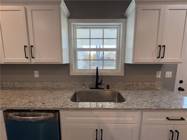 kitchen featuring stainless steel dishwasher, light stone counters, white cabinets, and sink