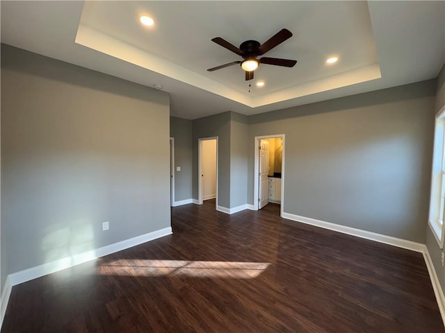 spare room featuring dark hardwood / wood-style floors, ceiling fan, and a tray ceiling