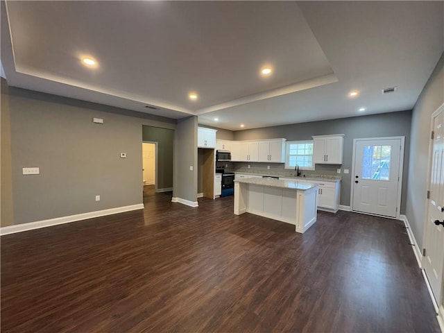 kitchen featuring black appliances, a kitchen island, a healthy amount of sunlight, and white cabinetry