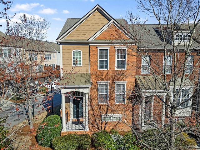 view of front facade with brick siding and a shingled roof