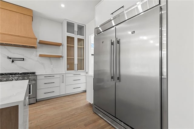 1857 Defoor Ave, Atlanta, GA 30318 - kitchen with high quality appliances, light wood-style floors, white cabinetry, backsplash, and custom exhaust hood