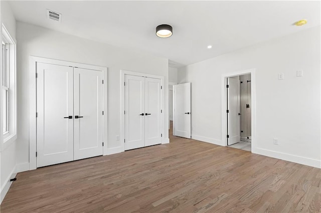 1857 Defoor Ave, Atlanta, GA 30318 - unfurnished bedroom featuring light wood-style floors, baseboards, two closets, and visible vents