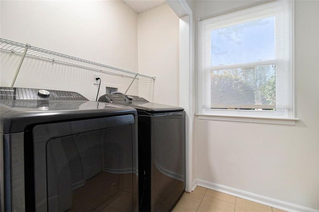 clothes washing area featuring light tile patterned floors, baseboards, separate washer and dryer, and laundry area