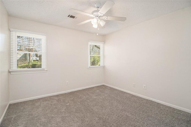 carpeted empty room with ceiling fan, baseboards, visible vents, and a textured ceiling