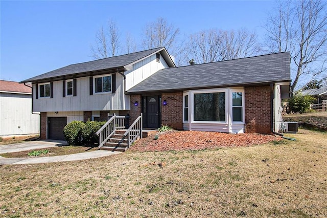 tri-level home featuring driveway, a front yard, a garage, brick siding, and central AC unit